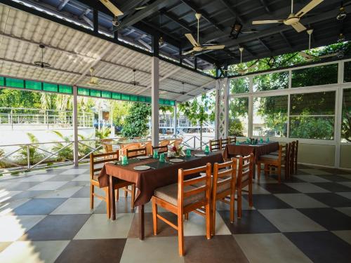 un restaurante con mesas, sillas y ventanas grandes en MGM Whispering Wind's Yelagiri en Yelagiri