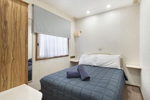 a bedroom with a bed with a blue blanket at Paradise Palms Caravan Park in Rathmines