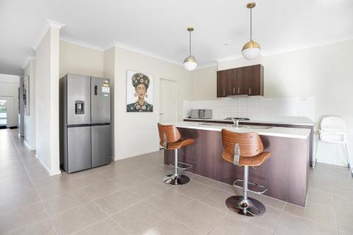 a kitchen with a refrigerator and two bar stools at Spacious Villa 7BRM 5-bathroom House Point Cook Double Storey in Point Cook