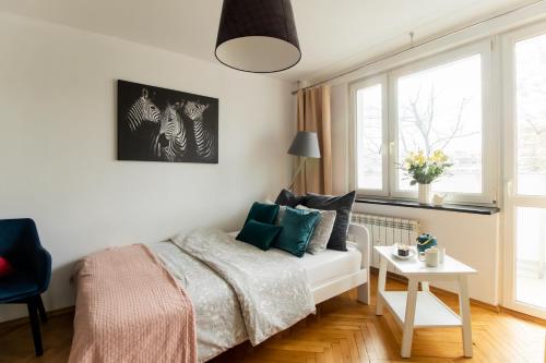 PiotrApartments II في وارسو: غرفة نوم بسرير وطاولة ونوافذ