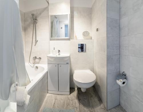 a white bathroom with a toilet and a sink at PiotrApartments II in Warsaw