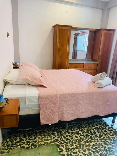 a bedroom with a bed with a pink blanket and a mirror at Casa Mágica in Flores