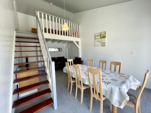 une salle à manger avec une table et des chaises et un escalier dans l'établissement Maison Confortable près de la Plage, Terrasse et Équipements Modernes, Calme - Brétignolles-sur-Mer - FR-1-231-61, à Bretignolles-sur-Mer