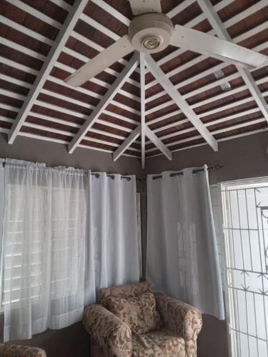 un ventilador de techo y una silla en la sala de estar en Country Manor, en Ocho Ríos