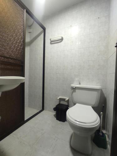 La salle de bains blanche est pourvue d'une douche et de toilettes. dans l'établissement Apartamento con jacuzzi En Bello - Cerca a Medellín, à Bello