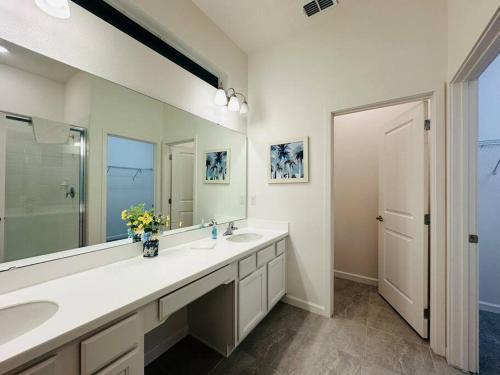 La salle de bains est pourvue de 2 lavabos et d'un grand miroir. dans l'établissement Cozy 12BR Pool House/BBQ/Sleep 24/Near Disney, à Kissimmee