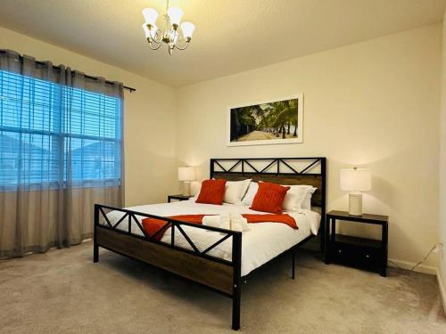 - une chambre avec un lit doté d'oreillers orange et une fenêtre dans l'établissement Cozy 12BR Pool House/BBQ/Sleep 24/Near Disney, à Kissimmee