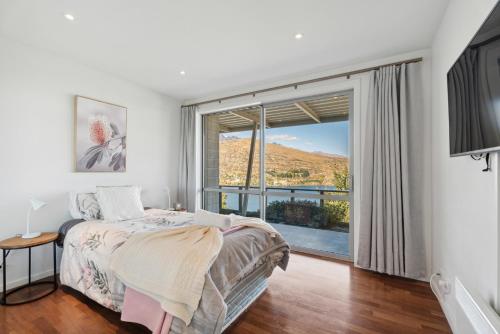 een slaapkamer met een bed en een groot raam bij Views On The Top - Queenstown Holiday Home in Queenstown