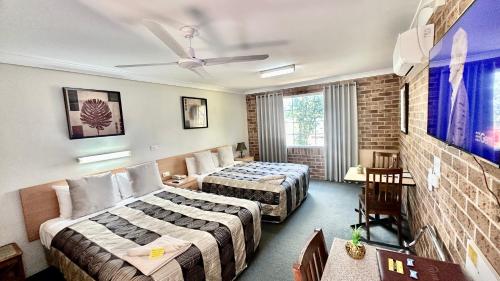 a hotel room with two beds and a tv at Golden Grain Motor Inn in Tamworth