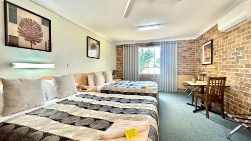 a hotel room with two beds and a brick wall at Golden Grain Motor Inn in Tamworth
