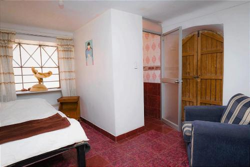 een slaapkamer met een bed, een raam en een stoel bij aguaymanto in Pisac