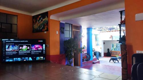 sala de estar con paredes de color naranja y pantalla grande en aguaymanto, en Písac