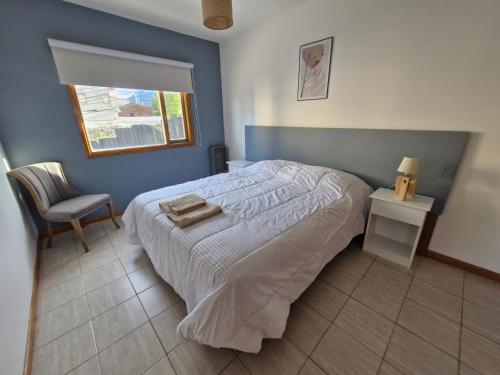 a bedroom with a bed and a chair and a window at Les Eclaireurs Room in Ushuaia