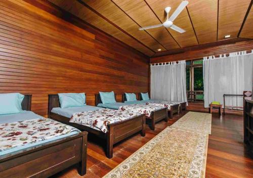 a row of beds in a room with wooden walls at Al Sakinah Resort in Bentong