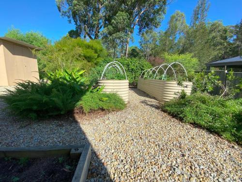 a garden with three white buckets on a gravel path at Charming Beach Getaway in Valla Beach
