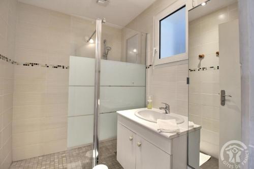 een witte badkamer met een wastafel en een douche bij Le rocher in Trélivan