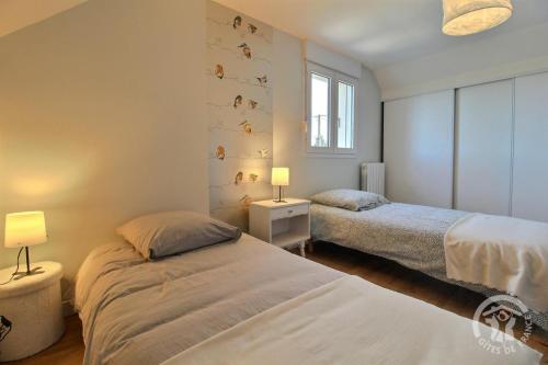twee bedden in een kleine kamer met twee lampen bij Le rocher in Trélivan