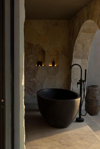 a bathroom with a black tub in a stone wall at SIVANA, Hotel Boutique with ocean or garden views - Adults only in Uluwatu