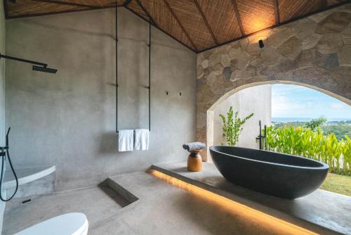 a bathroom with a large tub and a window at SIVANA, Hotel Boutique with ocean or garden views - Adults only in Uluwatu