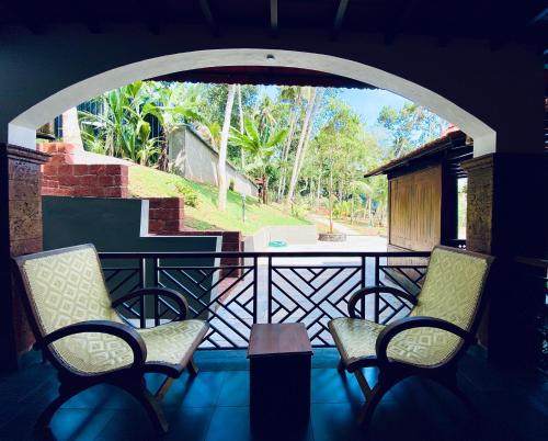 two chairs sitting on a balcony with an archway at JEEVAN HOMESTAY kovalam in Kovalam