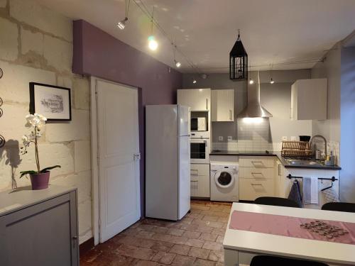 une cuisine avec un réfrigérateur blanc et une table dans l'établissement Gîte 18ème avec jardin, jeux, et ateliers cuisine près de l'Abbaye de Pontlevoy. - FR-1-491-349, à Pontlevoy