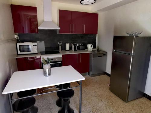 La cuisine est équipée de placards rouges, d'une table blanche et d'un réfrigérateur. dans l'établissement Séjour Bucolique en Sologne: Gîte de Plain-Pied avec Étangs et à Proximité des Châteaux de la Loire - FR-1-491-354, à Huisseau-sur-Cosson