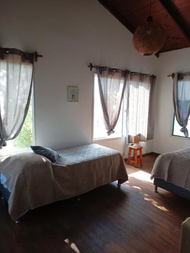 a bedroom with two beds and two windows at Casa 2 pisos Para 5 personas toda equipada in Colonia del Sacramento