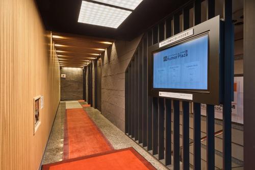 a hallway with a television on the wall at Sauna & Capsule Hotel Rumor Plaza in Kyoto