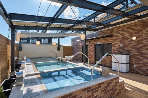 a swimming pool in the middle of a patio with a building at Sauna & Capsule Hotel Rumor Plaza in Kyoto