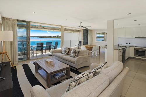 a living room with a couch and a table and a kitchen at Noosa Harbour Resort in Noosa Heads