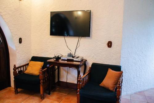 two chairs and a table with a television on a wall at Finca Ana Isabel 
