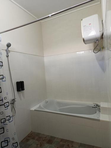 a white bath tub in a bathroom with a paper towel dispenser at Made Oka Homestay and Warung in Munduk