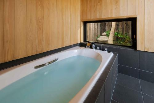 uma banheira na casa de banho com uma janela em Hatoba an Machiya House em Quioto