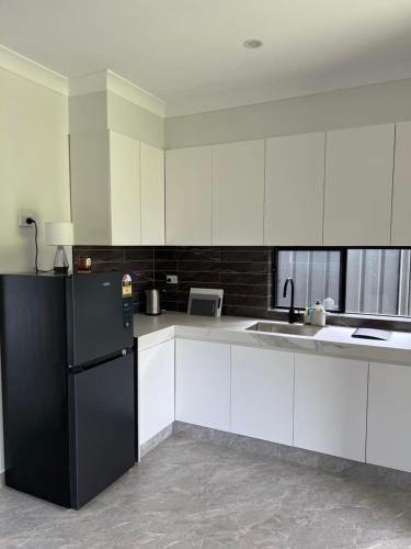 a kitchen with white cabinets and a black refrigerator at Little house with private garden in Padstow