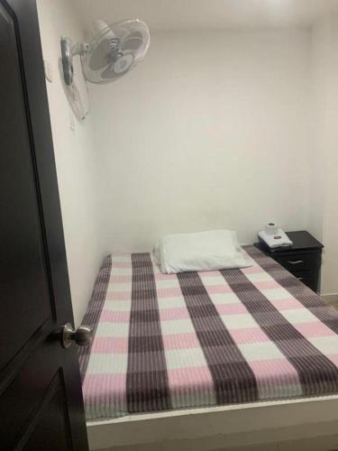 ein kleines Bett mit einer rosa und schwarzen karierten Decke in der Unterkunft Hotel La Fresa L&G in Pereira