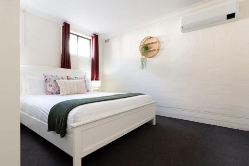a white bedroom with a bed with a window at Riverside Gem with Parking & WiFi in Alanvale
