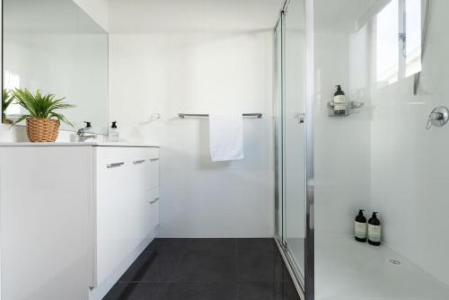a white bathroom with a shower and a sink at Riverside Gem with Parking & WiFi in Alanvale