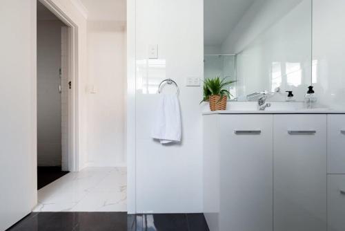 a white bathroom with a sink and a mirror at Riverside Gem with Parking and WiFi in Alanvale