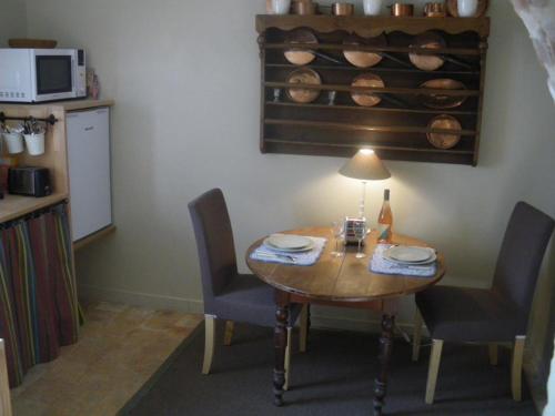 une cuisine avec une table avec des chaises et une lampe dans l'établissement Charmante maison avec jardin privatif, proche des Châteaux de la Loire, animaux acceptés - FR-1-491-422, à Monteaux