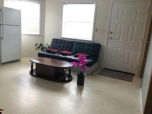 a living room with a black couch and a table at Cozy 1 bedroom 1 bath guest suite in a house in Burnaby