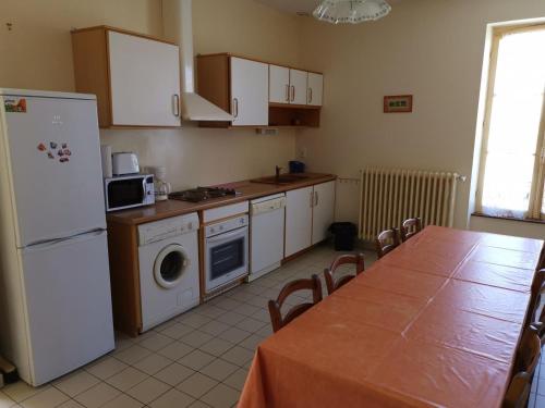 a kitchen with a table and a white refrigerator at Ancienne maison de maître rénovée, 6 pers, au cœur de la Sologne avec cour fermée et équipements modernes - FR-1-491-412 in Souvigny-en-Sologne
