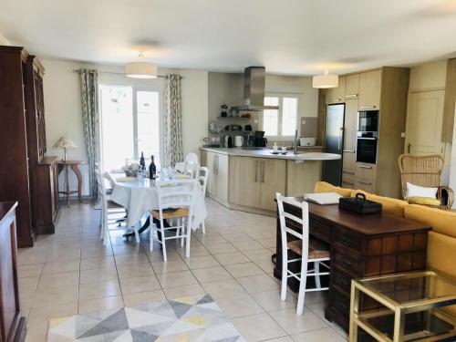 une cuisine et un salon avec une table et un canapé dans l'établissement Gîte familial de plain-pied avec grande terrasse, jardin clos et équipements complets à Vallières-les-Grandes - FR-1-491-423, à Vallières-les-Grandes