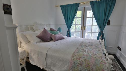 a bedroom with a bed with pillows and a window at Juniper Corner-Hunter Valley-A Step back in time!-7 mins to Vineyards in Cessnock