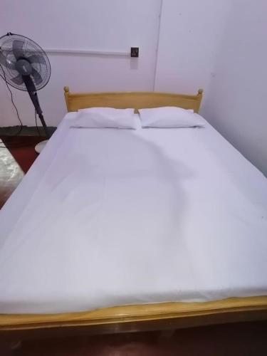 ein weißes Bett in einem Zimmer mit einem Ventilator in der Unterkunft Sobadahama ( The Nature Rest ) in Diwulankadawala