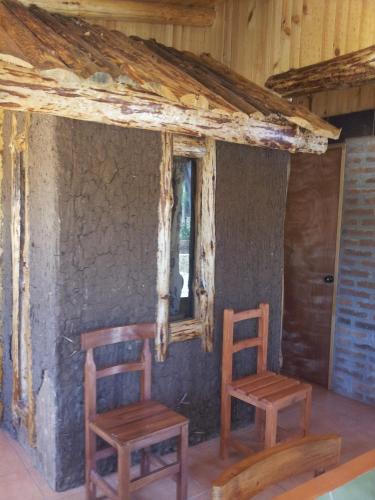 two wooden chairs sitting in the corner of a room at Cabañas Rukas Licantén in Licantén