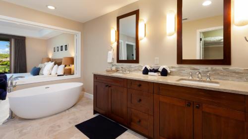 a bathroom with a tub and a large mirror at MAUNA KEA SUNRISE Distinguished 4BR KaMilo Home with Private Beach Pass in Waikoloa