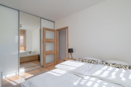 biała sypialnia z łóżkiem i lustrem w obiekcie CITYSTAY Wróblewskiego Apartament z parkingiem! w Łodzi