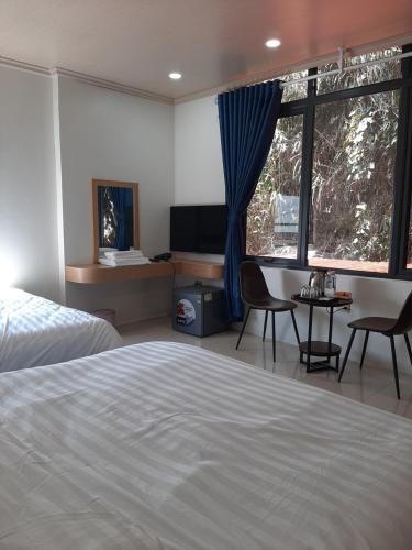 a bedroom with a bed and a desk and a window at Galaxy Hotel in Tam Ðảo