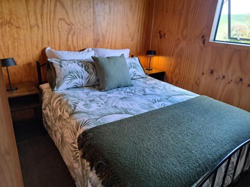 a bedroom with a bed with a blue comforter at Crinkly Cottage in Te Kuiti