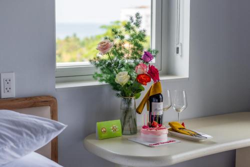 a table with a vase of flowers and a bottle of wine at The Up Hotel Phu Quoc Island - The Poolside Escape in Phu Quoc
